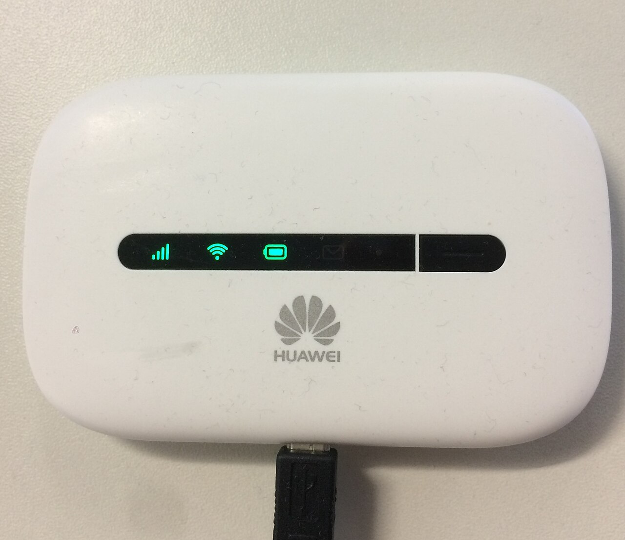 A white Huawei pocket Wi-Fi hotspot with signal and Wi-Fi lights on, plugged into a USB cable.