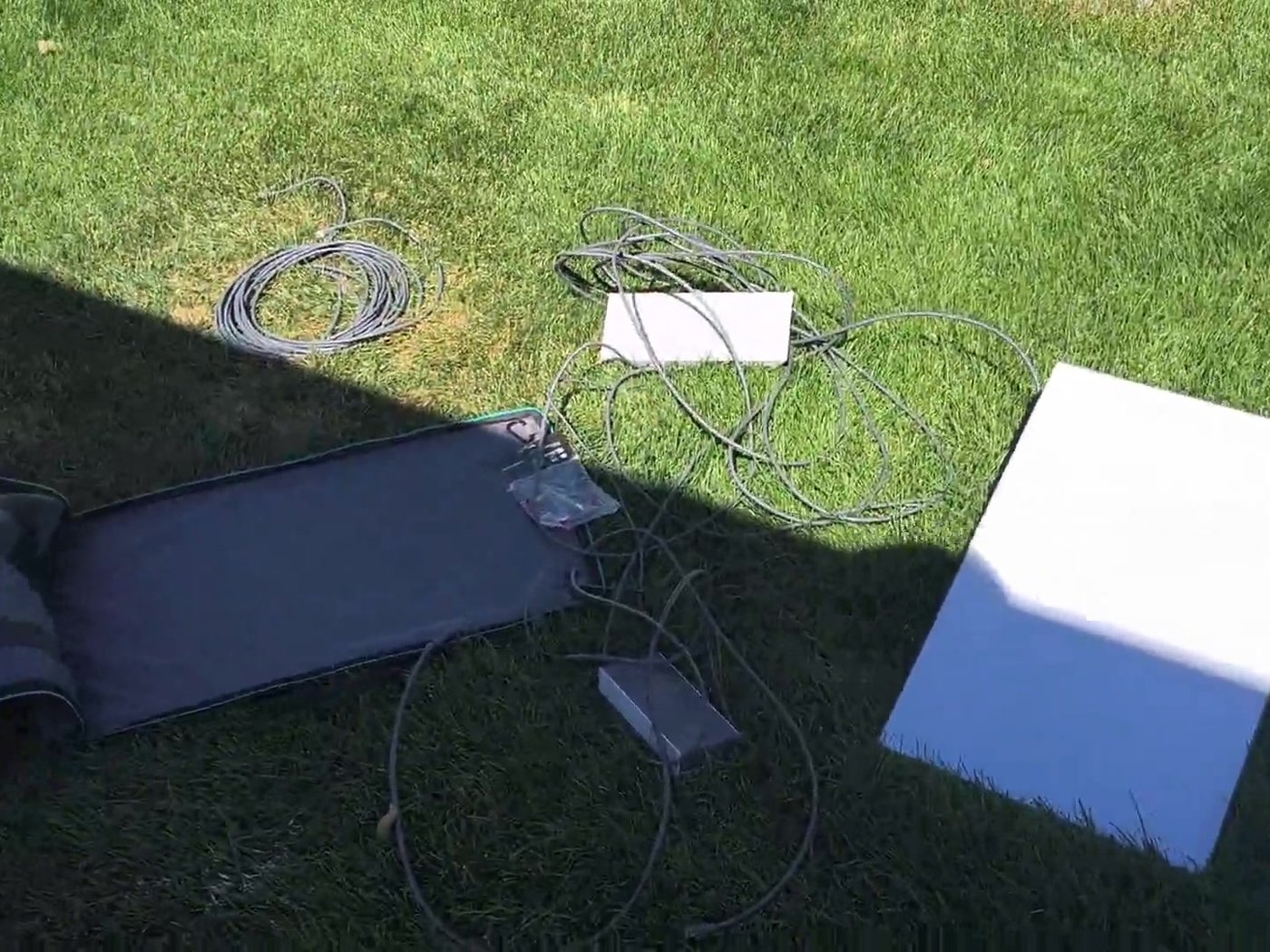 Starlink standard dish, case, and router cables laid out on grass next to our RV